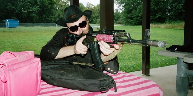 Eine Person mit rosa Handtsche und Gewehr am Schießstand
