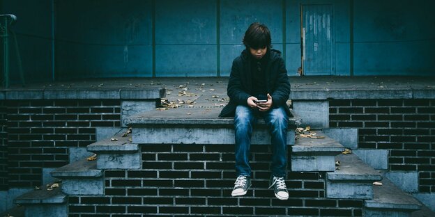 Ein Junge allein mit Smartphone