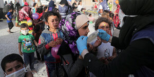 Eine Hilfsorganisation verteilt Schutzmasken, Kinder stehen in einer Schlange