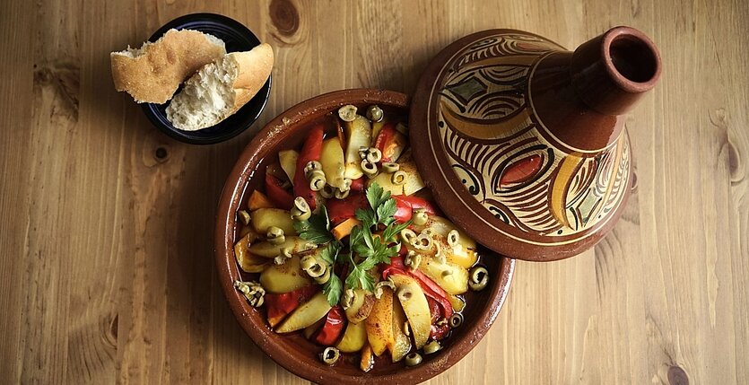 Ein Tontopf mit Tajine und ein kleiner Teller mit Weißbrot