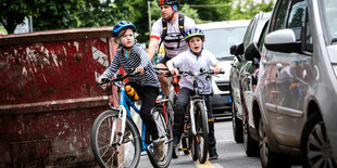 Drei Radfahrer versuchen einen Baucontainer auf einem Radweg zu umfahren