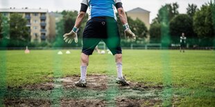 Ein Torwart steht im Matsch auf einem Amateurplatz in Berlin