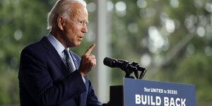 Joe Biden, seitlich fotografiert, steht an einem Redepult und hebt den Finger.