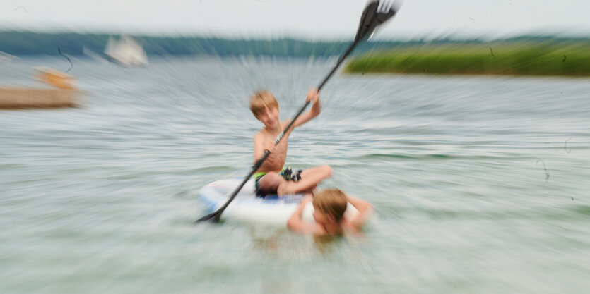 Zwei Kinder spielen auf dem Wasser.