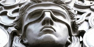 Bildhauerei zeigt Kopf der Justizia an einem Gerichtsgebäude