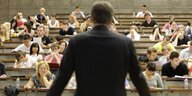 Rückansicht eines Mannes, der vor seinen Studenten im Hörsaal steht
