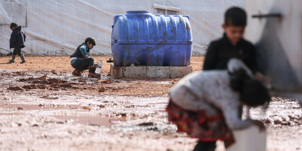 Zwei syrische Kinder an einem schmutzigen Wassereimer