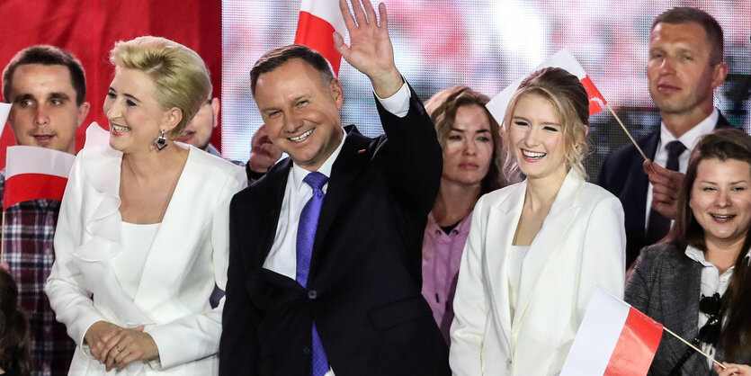 Präsident Duda mit anderen Personen winkend auf einer Bühne.