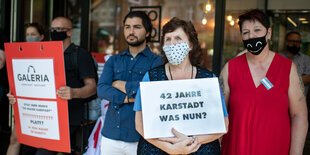 Mehrere Demontrantinnen mit Gesichtsmaske halten Schilder hoch. Auf einem gelben Schild steht: Karstast muss bleiben bei LEO.