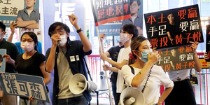 Protestierende mit Atemschutzmasken und Schildern
