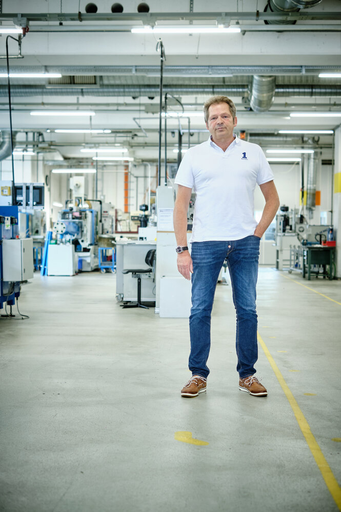 Mann in Jeans und weißem Shirt in einer Maschinenhalle