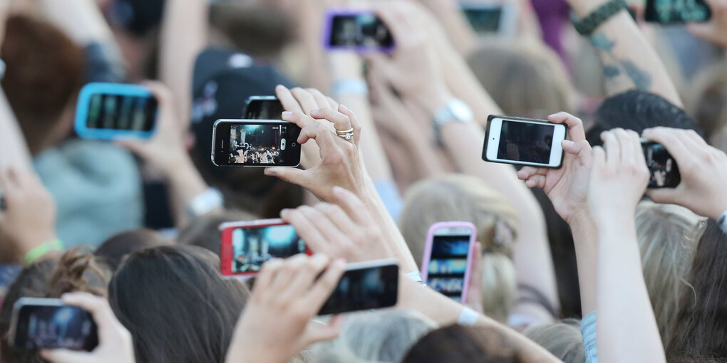 Viele Menschen fotografieren mit einem Smartphone einen Künstler