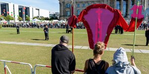 Drei Demonstranten halten ein Banner, das eine Mittelfinger zeigende Vulva darstellen soll. Sie demonstrieren damit gegen die Abtreibungsgegner vor dem Bundestag