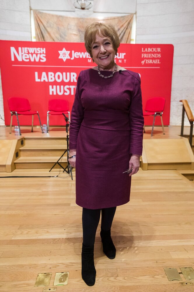 Eine Frau in einem roten Kleid steht vor einem Banner