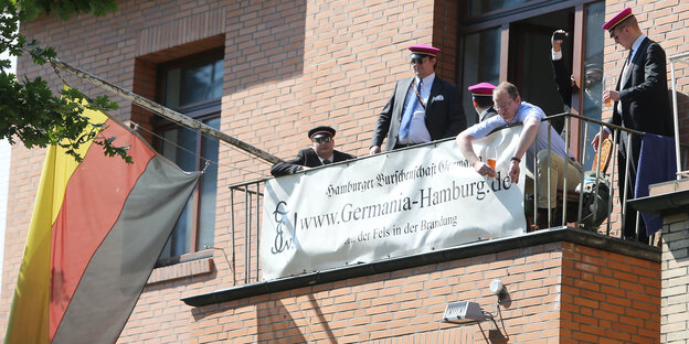 Männer mit Mützen auf einem Balkon mit Deutschlandfahne
