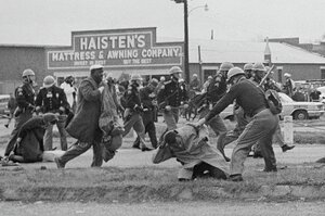 Historische Aufnahme von der Attacke von Polizisten gegen Demonstrierende in Selma. Ein Polizist holt mit dem Schlagstock aus, unter ihm liegt John Lewis. Im Hintergrund flüchten Menschen.