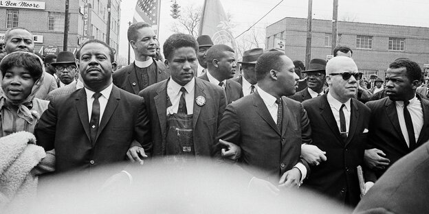 Schwarzweiß-Aufnahme von Bürgerrechtlern, die sich die Arme untergehakt haben, u.a. Martin Luther King und John Lewis