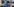 Frau mit Pexiglasgesichtsschutz, Maske, Ganzkörperschutz und Handy in einem Krankenhaus