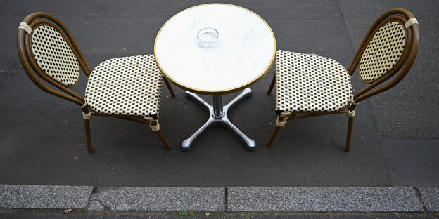 Ein Tisch mit zwei Stühlen steht auf der Töngesgasse in der Frankfurter Innenstadt vor einem Café.
