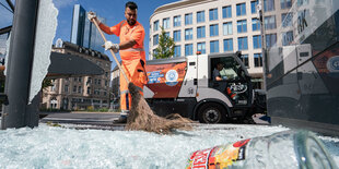 Scherben werden zusammengekehrt von einem Mitarbeiter der Stadtreinigung