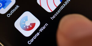Corona Warn App Symbol und ein Finger auf einem Smartphone