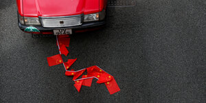 Chinesische Flaggen am Boden unter einem roten Wagen