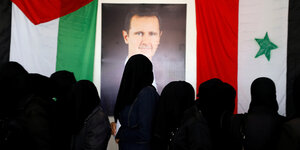 Schwarz verhüllte Frauen vor einem Assad Plakat