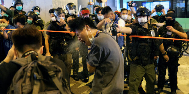 Sicherheitsbeamte setzen in Hongkong Tränengas gegen einen Demonstranten ein.