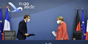 Macron und Merkel mit Masken vor einer blauen Wand