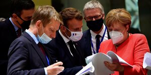 4 Männer und Angela Merkel schauen mit Mundschutz auf ein SChriftstück