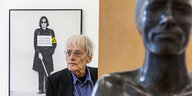 Künstler Timm Ulrichs steht in seiner Ausstellung umringt von seiner Kunst für ein Porträt leicht zur Seite blickend