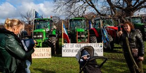 Frauen und ein Kind machen vor Traktoren Fotos
