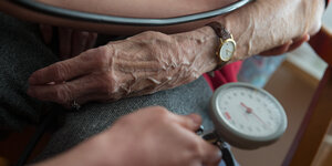 Eine Frau bekommt den Blutdruck gemessen, man sieht die Arme