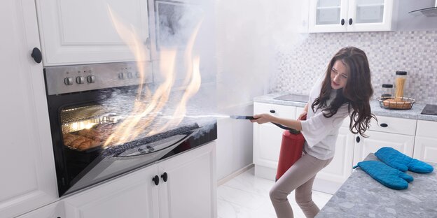 Eine Frau löscht einen Brand in ihrem Ofen mit einem Feuerlöscher