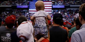 Frau hält Kind in QAnon-Shirtss bei einer Wahlveranstatlung von Trump in Pennsylvania 2018