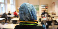 Schülerin mit Kopftuch sitzt in einem Klassenraum