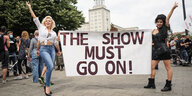 Suzy (l) und Rachel, zwei Double-Darstellerinnen aus dem Estrel-Hotel, halten bei einer Demonstration der Veranstaltungsbranche ein Plakat mit der Aufschrift "The Show must go on!"