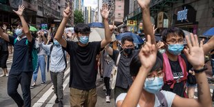 Protestierende, die als Symbol fünf Finger der einen Hand und einen Finger der anderen in die Luft halten