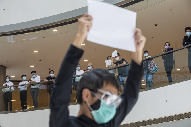 Ein junger Demonstrant hebt ein weißes Blatt nach oben