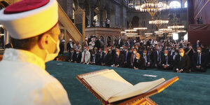 Ein Imam liest aus dem heiligen Buch Koran, dem heiligen Buch der Islams, vor, während Würdenträger, darunter der türkische Präsident Recep Tayyip Erdogan (2.v.r) an den Freitagsgebeten in der Hagia Sophia im historischen Sultanahmet-Viertel teilnehmen
