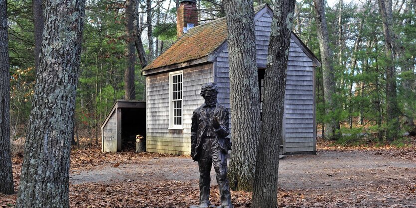 Ein einfaches Haus im Wald, davor eine Statue