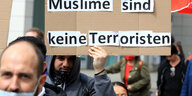Demonstranten mit Plakat "Muslime sind keine Terroristen"