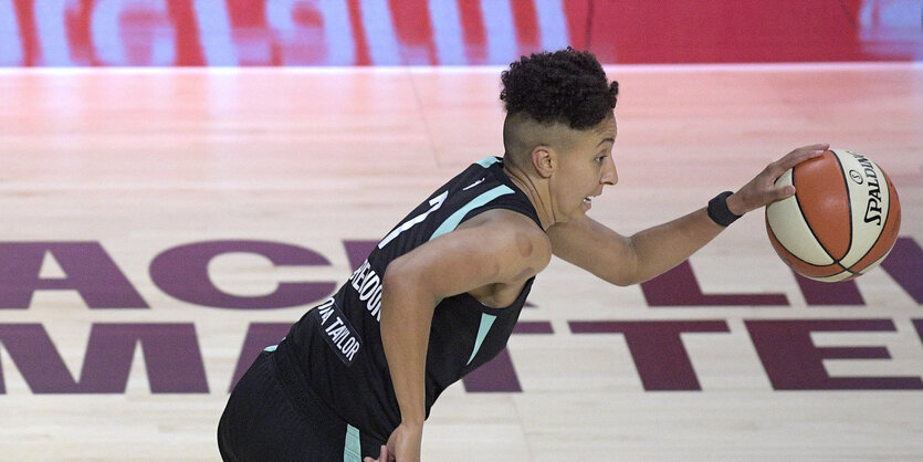 Layshia Clarendon rennt mit einem Basketball durch eine Sporthalle, der Blick angestrengt