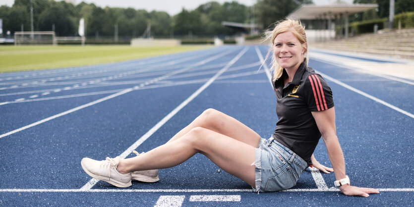 Annika Schleu sitzt auf einer blauen Tartanbahn im Olympiapark in Berlin