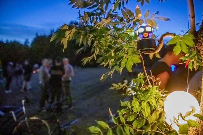 Eine bunt leuchtende Discokugel dreht sich in einem Gebüsch in dem Park Hasenheide in Berlin-Neukölln.