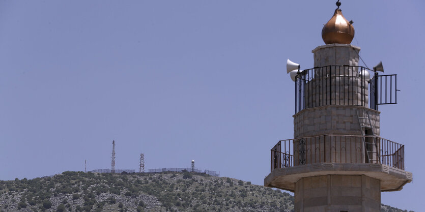 Ein Turm, dahinter ein Berg und blauer Himmel