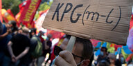 Ein Teilnehmer einer Demonstration hält ein Schild mit der Aufschrift "KPG (m-l)"