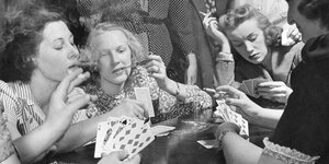 Frauen spielen Karten und rauchen Zigaretten