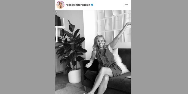 Die Schauspielerin Reese Witherspoons lächelt mit nach oben gestreckten Armen in die Kamera