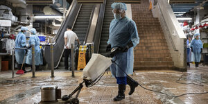 Mitarbeiter in Schutzkleidung poliert Fußboden